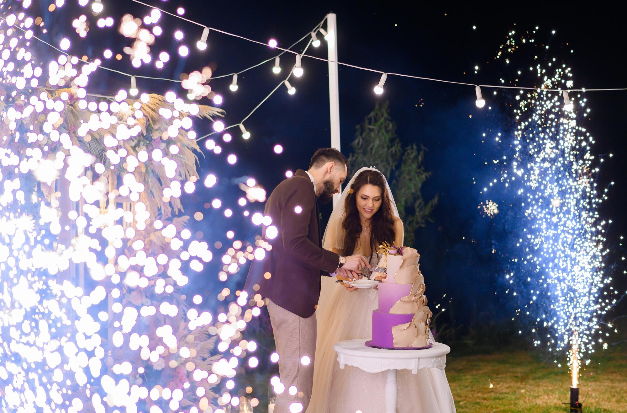 newlyweds-evening-celebration-wedding-cutting-cake-outdoors